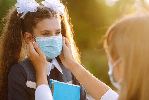 Mother puts on a protective sterile mask on a schoolgirl's. COVID-19 quarantine.