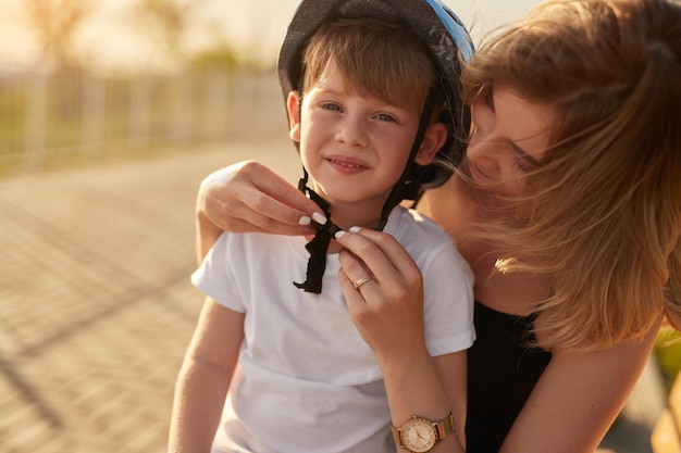 Mother putting safety helmet on son