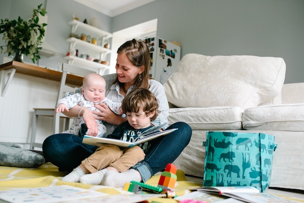 Mother reading book with children sitting on the floor