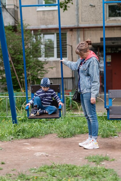 A mother rocks her baby on a swing in the yard