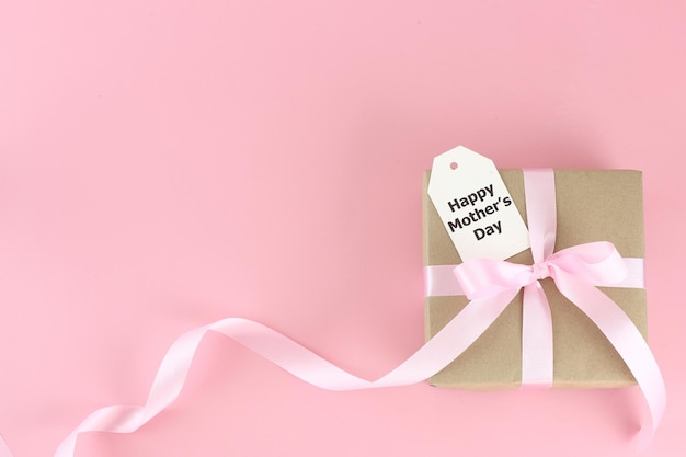 Photo mother's day background top view of gift box with pink bows long ribbon beautiful flowers and card on pastel pink background with copy space