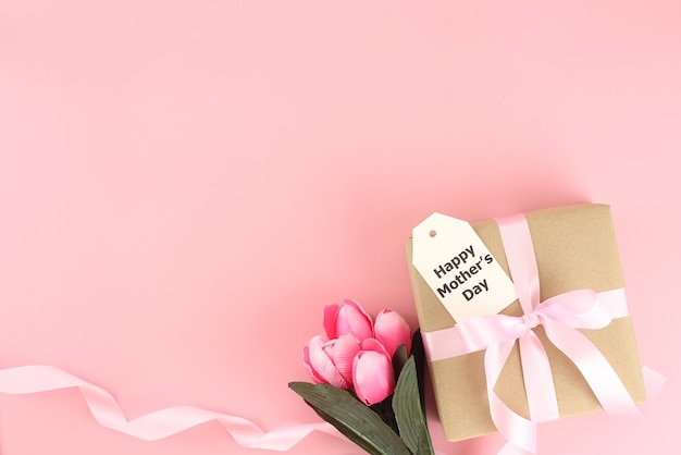 Mother's day background Top view of gift box with pink bows long ribbon and beautiful flowers on pastel pink background with copy space