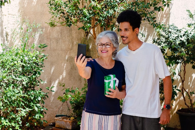 Mother's day Caucasian mother and her black son taking a selfie photo in the garden at home