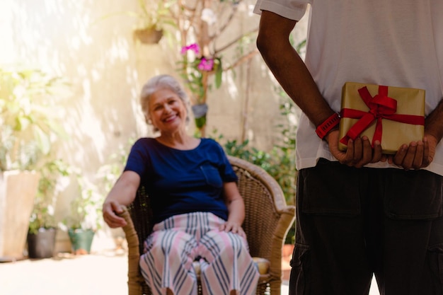 Mother's day caucasian mother and her black son with gift in the house garden happy interracial family