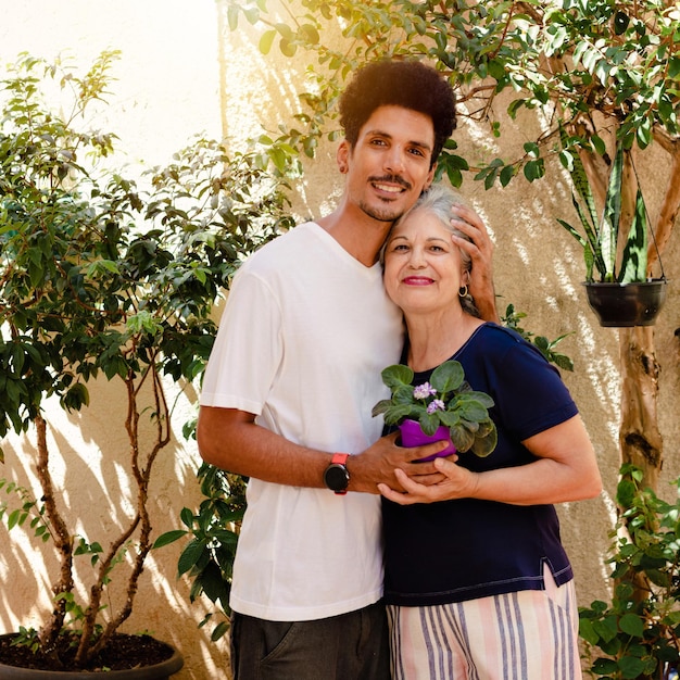 어머니의 날 백인 어머니는 집 정원에 있는 흑인 아들에게서 꽃을 받습니다.