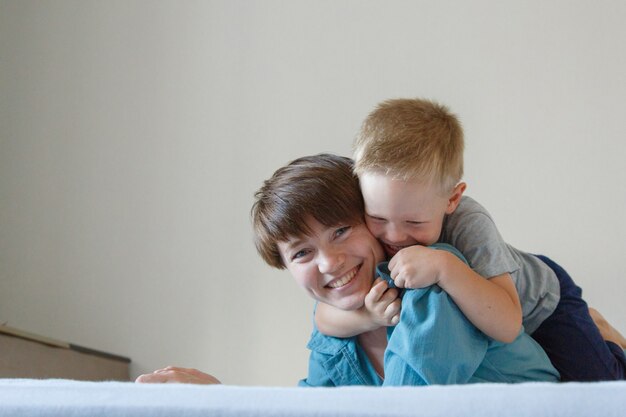 Festa della mamma. l'amore della madre. una donna felice e un ragazzo in un abbraccio di stoffa blu