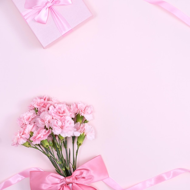 Festa della mamma san valentino sfondo concetto di design bellissimo bouquet di fiori di garofano rosa su tavolo rosa pastello vista dall'alto spazio piatto per la copia