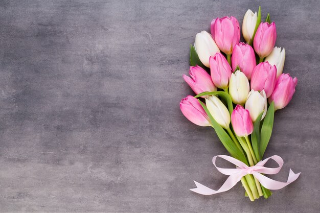 Festa della mamma, festa della donna, pasqua, tulipani rosa, regali su sfondo grigio.