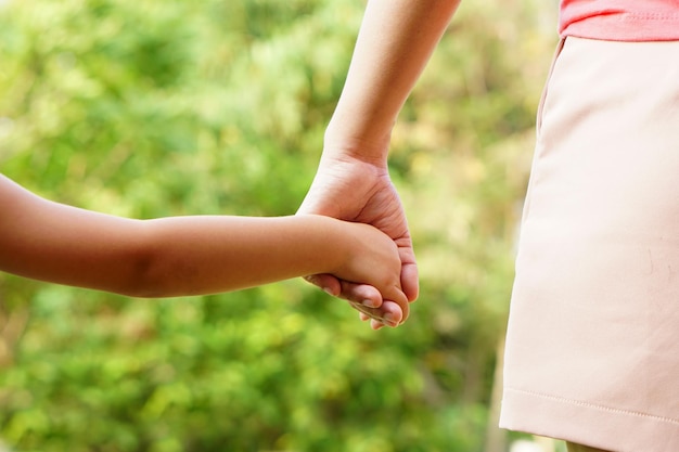 Foto mano della madre che tiene la mano di una bambina su sfondo bokeh concetto di amore e famiglia