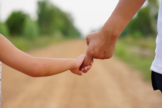 Mother's hand holding a little girl's hand on bokeh background Love and family concept