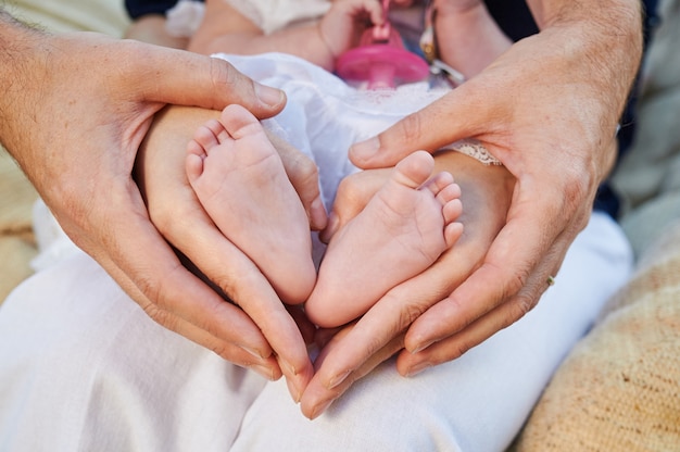 Mother's hands forming a heart among her baby's feet