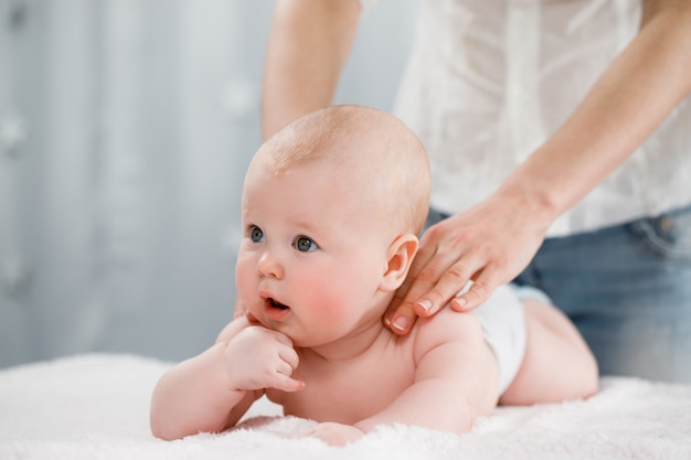 Le mani della mamma massaggiano i muscoli della schiena del suo bambino.