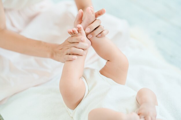 Mother's hands supporting the baby's feet in the room