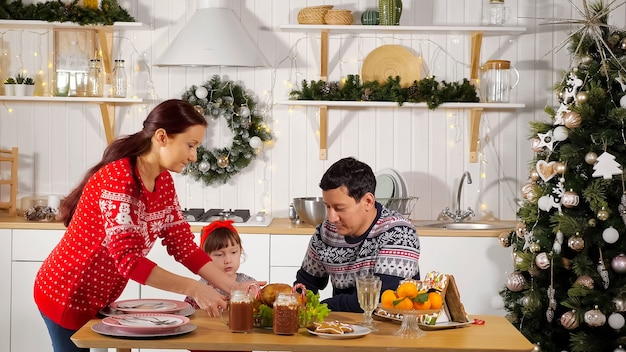 Mother sets table and father with daughter waits for dinner