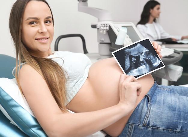 Фото Мать показывает ультразвуковой экран будущего ребенка в клинике