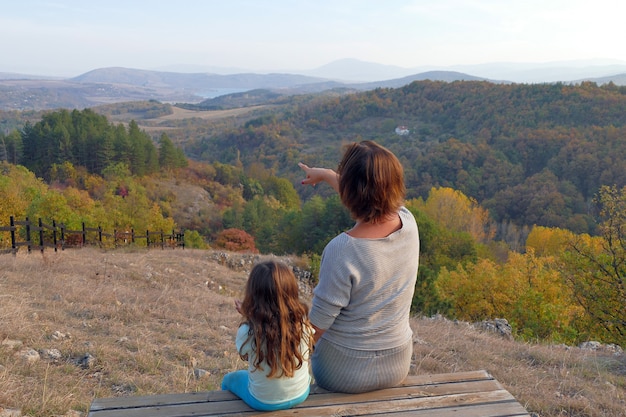 A mother shows a 4 and a half year old girl a view of a forest