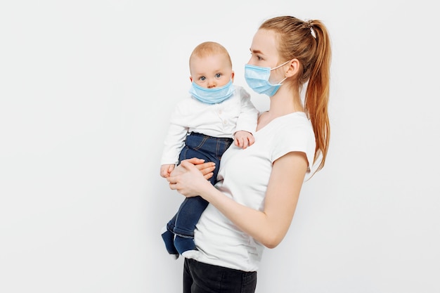 A mother and a small baby in their arms in medical protective masks against viral diseases during the coronavirus epidemic