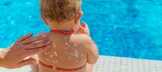 Mother smeared sunscreen on the back of the child Selective focus