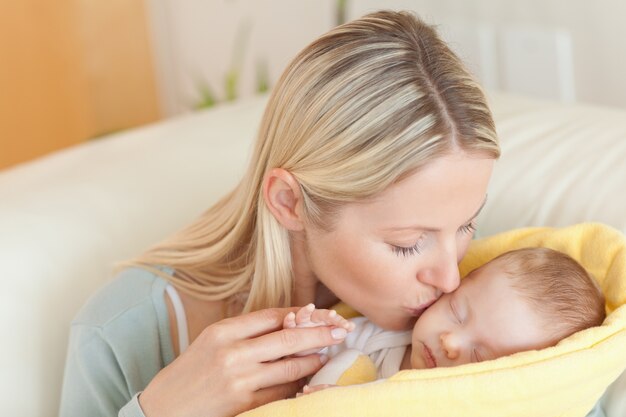 彼女の赤ちゃんにキスをするソファーの母