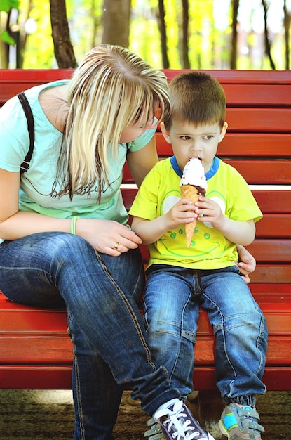 Foto madre e figlio stanno giocando nel parco giochi, ridendo, divertendosi. gelato. felice stile di vita familiare. ragazzo