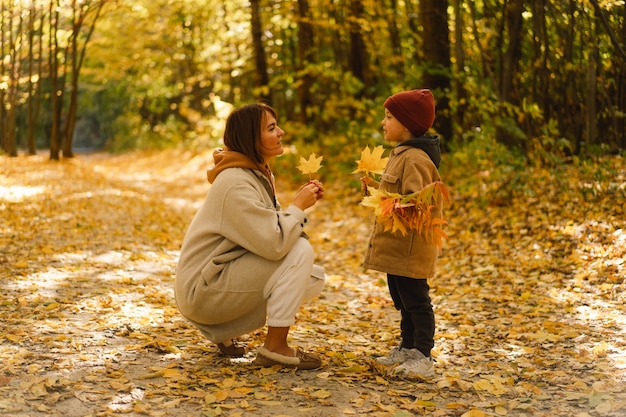 엄마와 아들은 아이들과 함께 가족을 위한 가을 숲 가을 야외 활동을 걷고 있다