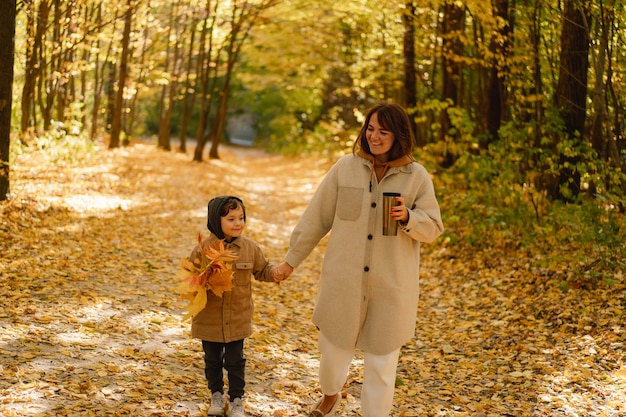 Mother and son are walking in the autumn forest autumn outdoor activity for family with kids