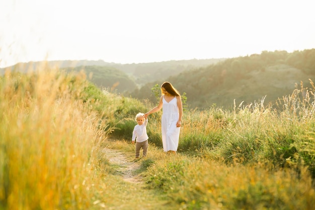 Mother and son are walking in the green field