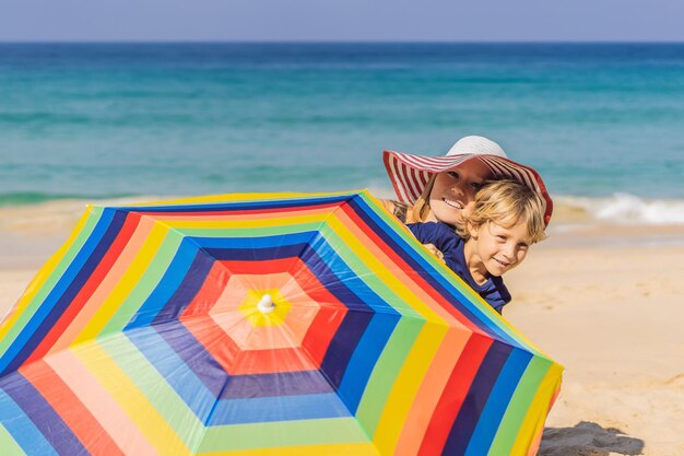 Mother and son on the beach in a hat and beach umbrella