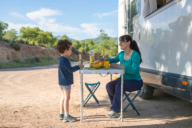 Mother and son at camping table next to motor home