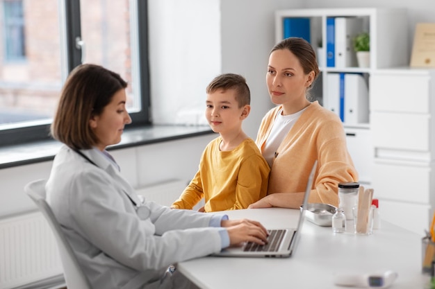 mother son and doctor with laptop at clinic