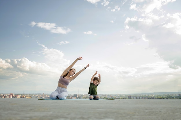 Mother and son doing exercise on the balcony in the background of a city