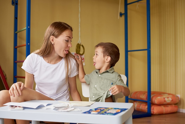 Mother and son draw at a table inside the room.