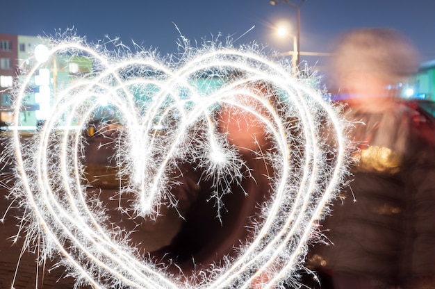 Mother and son drawing a heart with sparkle sticks. 