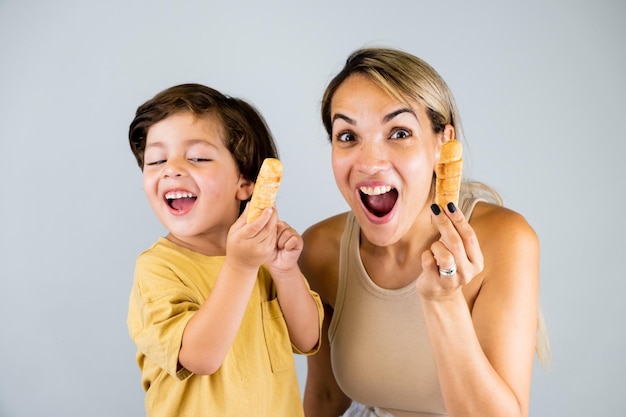 Mother and son enjoying and eating a Latin American snack called tequenos funny expressions on their faces