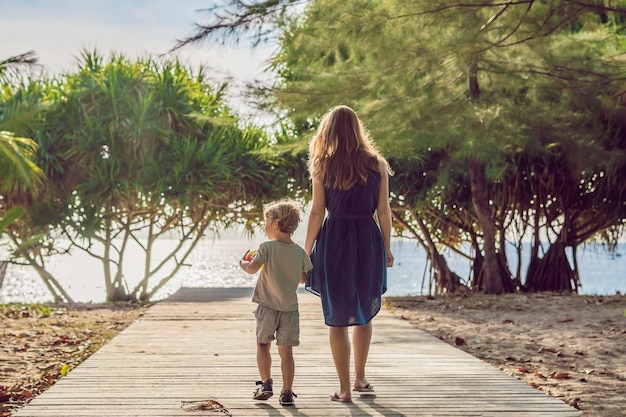 Mother and son go to the sea beach resort vacation on tropical beach path to beach