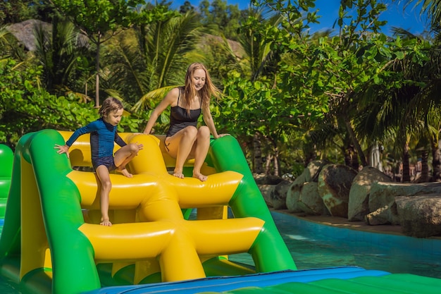 Mother and son go through an inflatable obstacle course in the pool