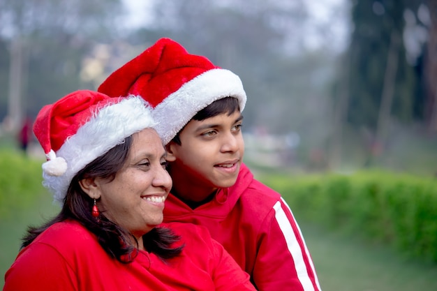 Mother and son happy together in Santa Claus caps,  Smiling and looking at a distance 