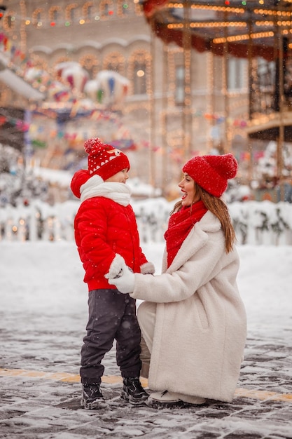 母と息子はカルーセルの背景にあるクリスマス マーケットで楽しんでいます。