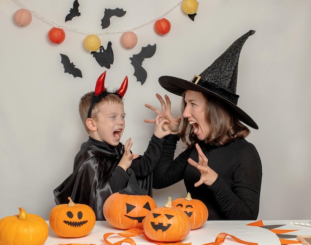 Mother and son have fun playing and celebrating Halloween in a witch and devil costume