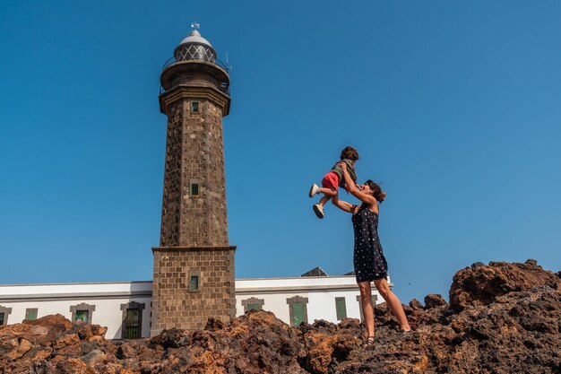 Mother and son having fun at the beautiful orchilla lighthouse in southwest el hierro canary islands