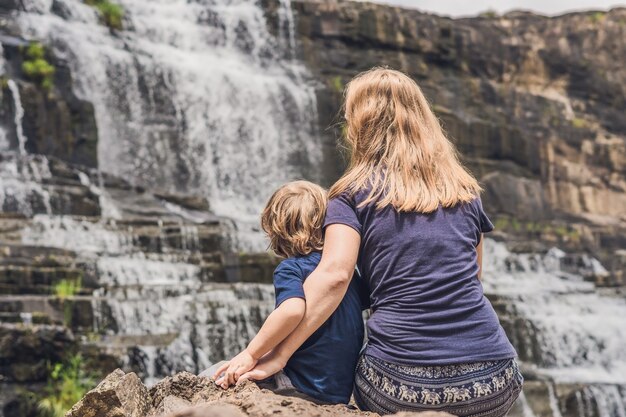 Mother and son hikers tourists on the background of amazing pongour waterfall