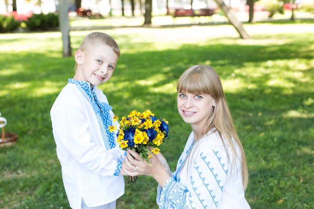A mother and son holding flowers in a park