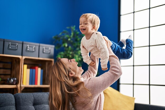 自宅のソファに座って空気中の子供を保持している母と息子