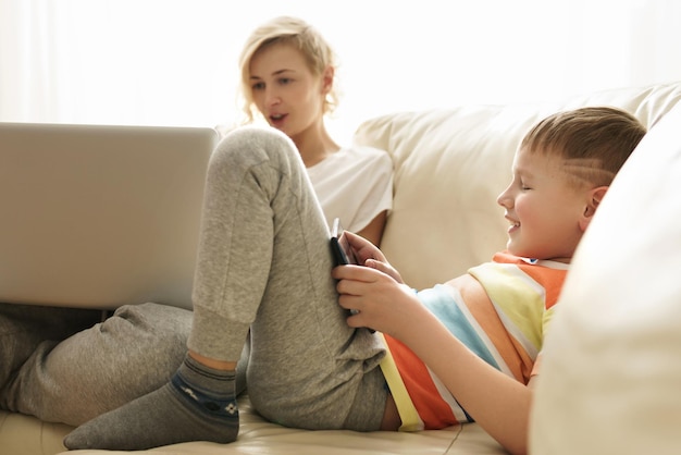 Foto madre e figlio a casa. il ragazzo sta imparando a usare un tablet pc.