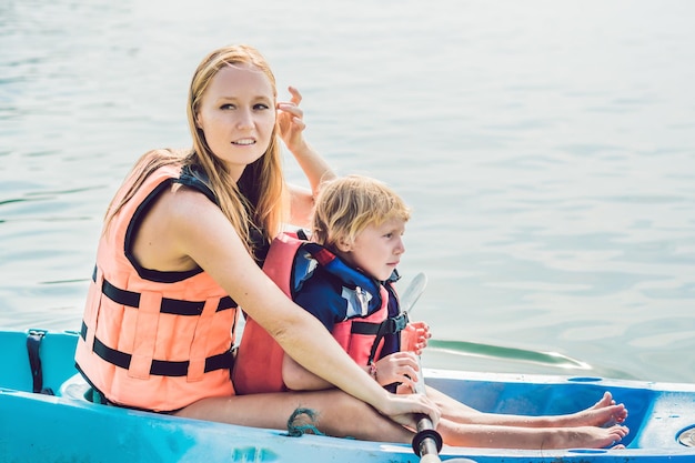 Mother and son kayaking at tropical ocean.