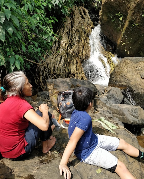 Foto madre e figlio guardano una cascata nella foresta