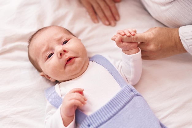 Mother and son lying on bed holding hands at bedroom