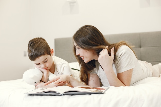 Mother and son lying on the bed reading a book.