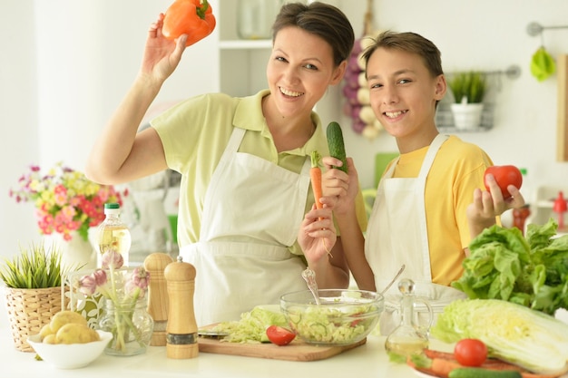 Мать и сын готовят свежий салат на кухне