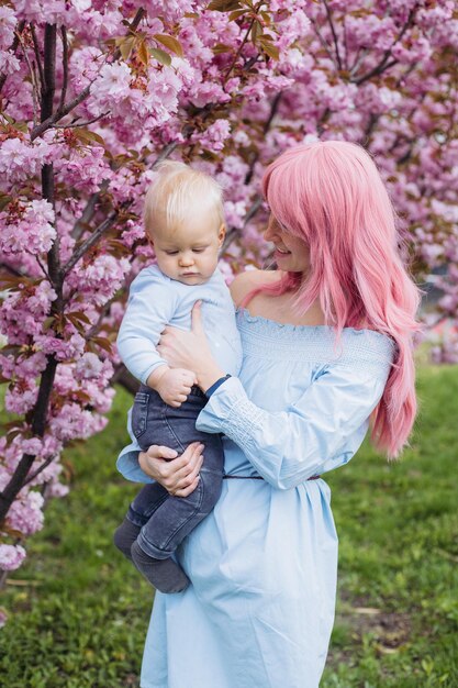 春の公園で遊ぶ自然の母と息子小さな男の子と母は、咲く桜の庭園で週末の活動で楽しい時間を過ごします